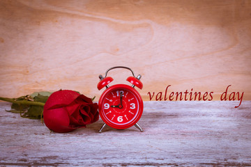 vintage watch and red rose on wooden background