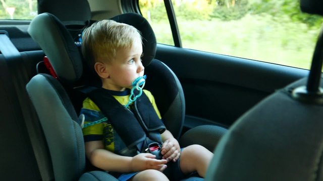 kid baby child boy toddler in the children's car seat in the car rides