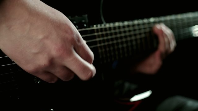 Man lead guitarist playing on electric guitar. Close-up. Zoom to fingerboard.