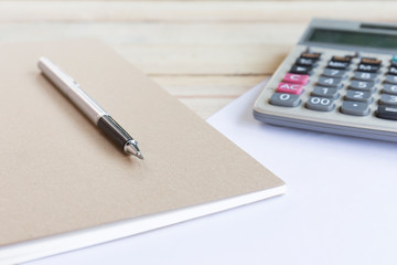 Blank white notebook with pen on wood desk. shallow depth of field