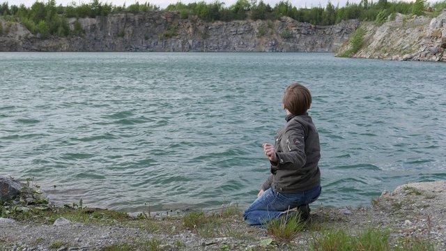 teen boy throwing stones into the water of the lake. Childhood dreams and memories. Ecology and environment, fresh air, clean water
