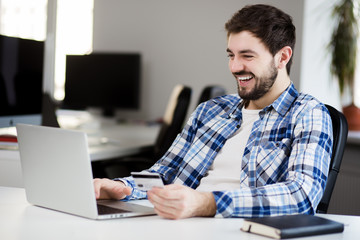 young man doing online shopping in office