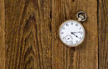 Fototapeta na wymiar Old pocket watch and key on the wooden background with blank spa