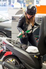 Obraz premium Frau tankt Roller auf der Tankstelle