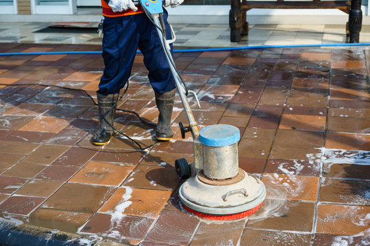People cleaning floor with machine.