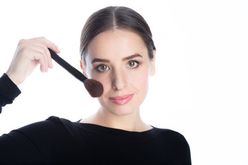 Obraz premium Beautiful woman holding a powder brush near her face, studio white