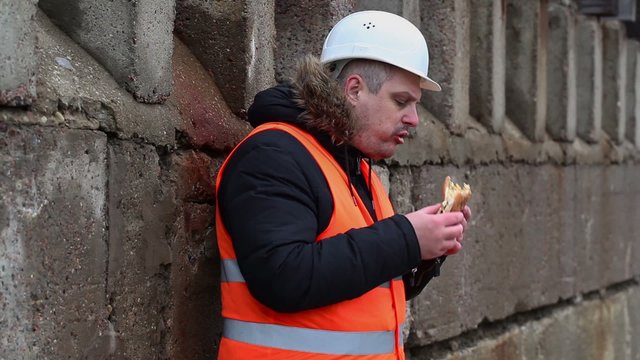 Worker eating hamburger at outdoor
