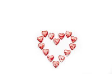 Red and white heart shaped chocolates arranged in heart on white background directly from above copy space