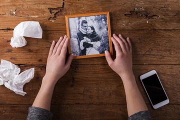 Unrecognizable sad woman holding broken picture of couple in love. 