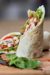 Mexican tortilla wrap with chicken breast and vegetables served on a wooden board 