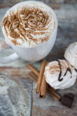 Hot coffee with marshmallows in a cup on the wooden background