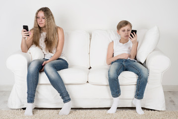 Obraz premium Boy and girl sitting on a sofa with a smartphone