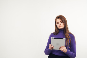 Naklejka premium Young and beautiful teenager girl holding an ipad tablet pc in her arms over grey background