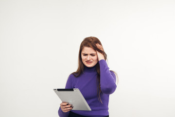 Young and beautiful teenager girl holding an ipad tablet pc in her arms over grey background