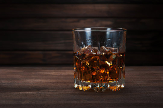 Glasses of whiskey on dark wood background