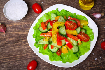Helpful Fresh Salad of cucumbers, tomatoes, pepper and lettuce dressed with olive oil.