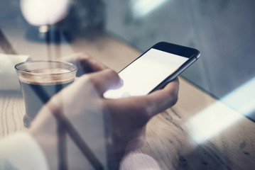 Close up of generic design smart phone holding in female hands for texting message. Cup coffee on the table