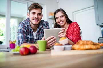 Obraz na płótnie Canvas Happy couple having breakfast and using tablet
