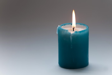 Fototapeta na wymiar Turquoise candle on gray gradient background. Macro view. soft focus. Memorial day concept. copy space