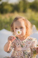 Little girl smelling a daisy