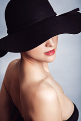 Woman in black dress and hat with bare shoulders