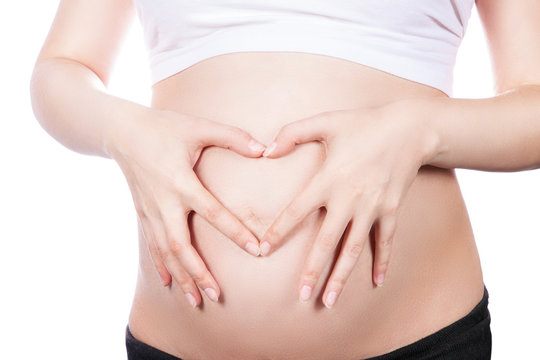 Pregnant Woman holding her hands in a heart shape on her baby bump. Pregnant Belly with fingers Heart symbol. Maternity concept.