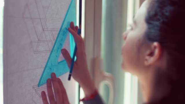 Teen girl tracing lines on plan
