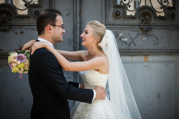 Happy couple, bride and groom posing and hugging, old door backg