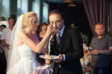 Happy, emotional newlyweds eat delicious wedding cake at recepti
