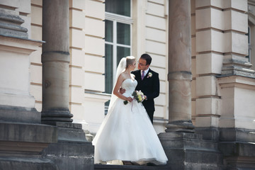 Fototapeta premium Sensual newlywed couple hugging near old building with columns