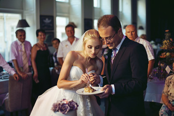 Happy, emotional newlyweds eat delicious wedding cake at recepti
