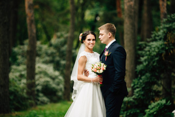 Beautiful bride and groom walking outdoors in park.