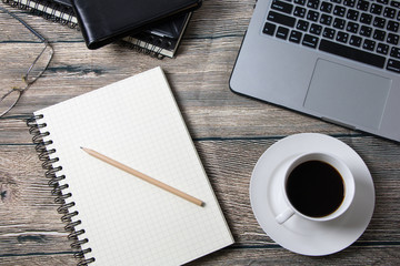 Working desk with coffee laptop glasses book notepad supplies and tablet  on wooden desk