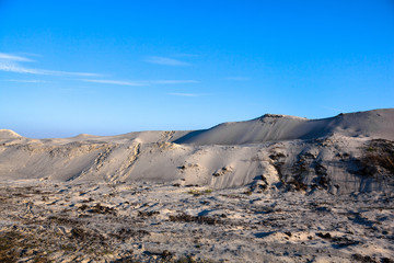 Gray sand dunes with the grass grown through the sandy surface