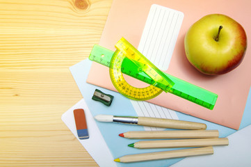 Notebooks, brush, colored pencils, ruler, sharpener, eraser on a wooden surface. School subjects...