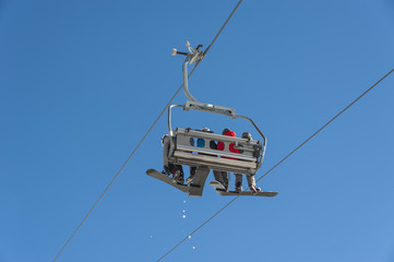 Skiers sitting on a chairlift at a ski resort.