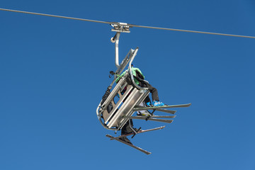 Skiers sitting on a chairlift at a ski resort.