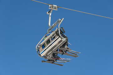 Skiers sitting on a chairlift at a ski resort.
