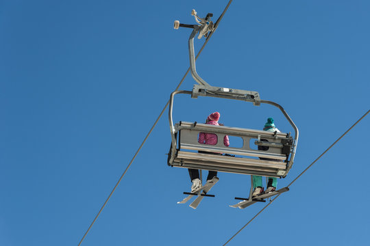 Skiers sitting on a chairlift at a ski resort.