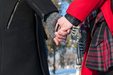 Young couple holding hands standing outdoors in winter, closeup