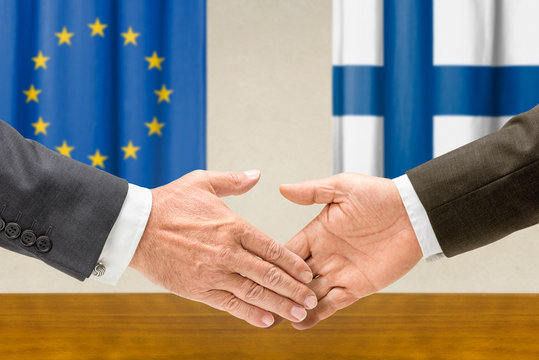 Vertreter der EU und Finnlands reichen sich die Hand