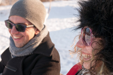 Young couple sitting on bench in park in winter and smiling