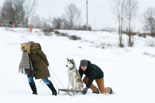 The girl and the guy carry a dog on sledge.