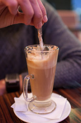Close up of hand mixing coffee with a spoon in the cup.