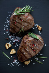 Top view of grilled filet mignon steaks, black wooden surface