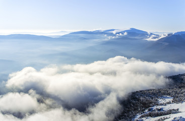 Winter landscape of a blue mountains and fluffy clouds in the valley. Carpathian Ukraine