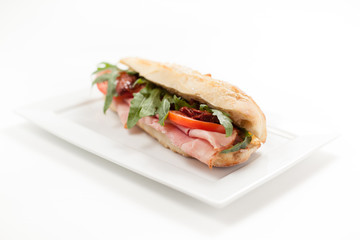 Italian sandwich Ciabatta with ham,  rucola, tomato on a white background