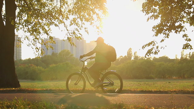 Slow motion shot of overweight man riding bike in the park, obesity problem