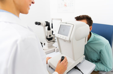 Fototapeta premium optician with autorefractor and patient at clinic