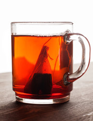 Tea bag in glass mug on wooden table